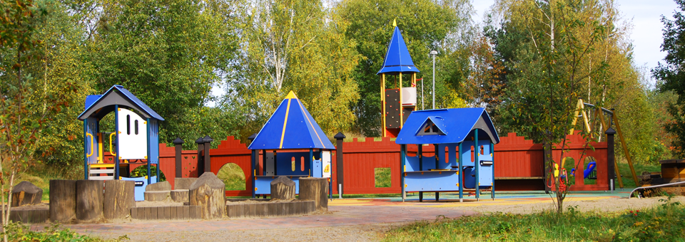 Färgglad lekpark med gröna träd i bakgrunden.